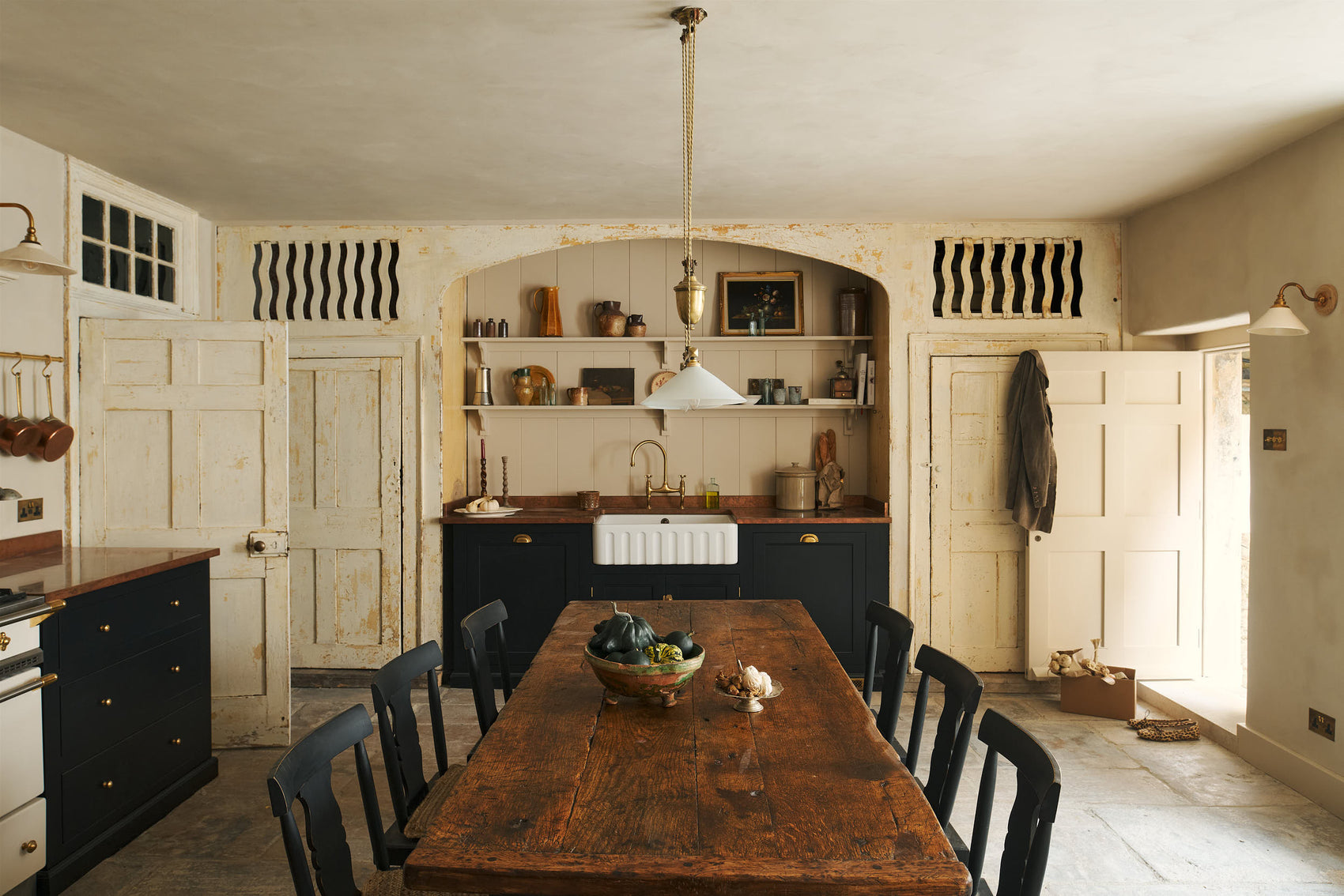 A rustic basement kitchen with sandy-coloured walls and a wooden table